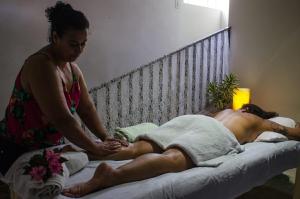 una mujer dándole un masaje a un hombre en una cama en Hostel Café en Alto Caparao