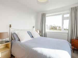 a white bedroom with a bed and a window at Yr Orsedd in Holyhead