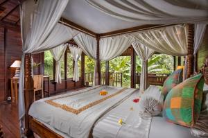 een slaapkamer met een groot bed met een baldakijn bij Secluded Jungle Villa in Ubud