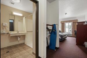 a hotel room with a bed and a bathroom at Stay USA Hotel and Suites in Hot Springs
