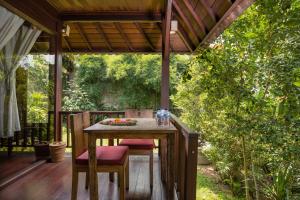 an outdoor table and chairs on a deck with trees at Secluded Jungle Villa in Ubud