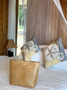 a bed with two pillows and a purse on it at Thiwson Beach Resort - SHA Extra Plus in Ko Yao Yai
