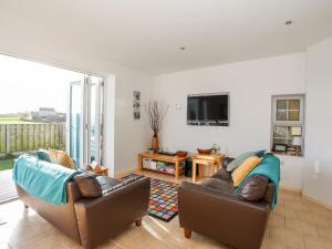a living room with two leather chairs and a television at Farm Cottage in Cemaes Bay