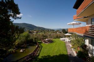einen Garten mit einem Tisch, Stühlen und einem Fluss in der Unterkunft St. Oswalderhof in Pörtschach am Wörthersee