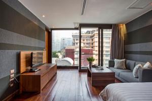 a hotel room with a bed and a tv and a couch at LUXX Langsuan Hotel - SHA Plus in Bangkok