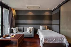 LUXX Langsuan Hotel - SHA Plus في بانكوك: غرفة نوم بسرير واريكة