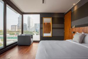 LUXX Langsuan Hotel - SHA Plus في بانكوك: غرفة نوم بسرير كبير ونافذة كبيرة