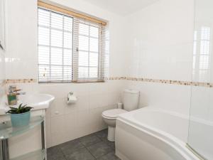 a white bathroom with a toilet and a sink at Farm Cottage in Cemaes Bay +24 photos