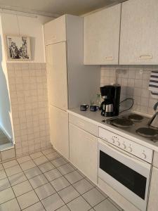 uma cozinha com armários brancos e um forno com placa de fogão em Citi Wohnung em Husum