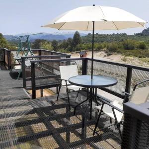 una mesa y sillas en un balcón con sombrilla en Apart hotel Pehuenia en Villa Pehuenia