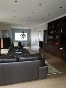 sala de estar con sofá de cuero y lámpara de araña en Bristow Luxury Suites With Back Up Power and Free Wi-Fi en Roodepoort