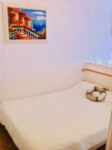 ein weißes Bett mit einem Bild an der Wand in der Unterkunft “L’alcova delle Sirene” in Bergeggi