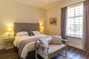 a bedroom with a large bed and a chair at The Lookout Guest House in Port Alfred