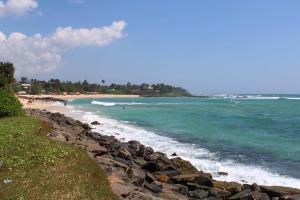 a beach with people swimming in the ocean at Colonial Surfing Villa Hostel & Home Stay in Midigama