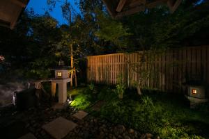 um jardim à noite com uma casa de pássaros e uma cerca em Yakakutei em Kirishima