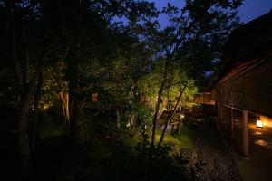 霧島的住宿－亞卡庫推旅館，享有树木庭院和建筑的夜景