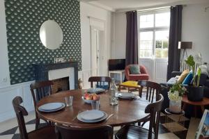 a dining room with a table and chairs and a fireplace at La maison d'à côté in May-sur-Orne