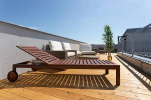 drewniany taras z kanapą i stolikiem kawowym w obiekcie Skyline Penthouse l LF44 w Wiedniu