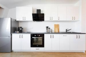 kuchnia z białymi szafkami i czarnym sprzętem AGD w obiekcie Skyline Penthouse l LF44 w Wiedniu +5 zdjęć