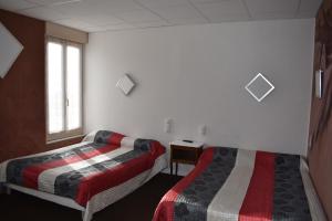 a hotel room with two beds and a window at Le Rider in Bort-les-Orgues