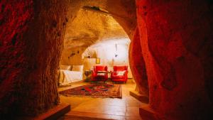 a room with a bed and chairs in a cave at Jerveni Cave Hotel in Mustafapaşa