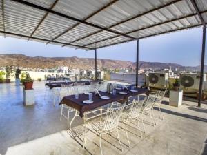 a patio with tables and chairs on a roof at Hotel Dior Jaipur in Jaipur