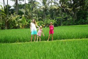 a woman and two little girls standing in a field at Santun Luxury Private Villas-CHSE CERTIFIED in Ubud