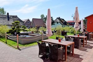 a patio with tables and umbrellas and a pool at Ferienwohnungen Moenchgut und Ruegen in Lobbe