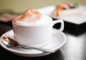 a cup of coffee sitting on a table with a spoon at Gately Inn Entebbe in Entebbe