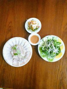 quatro pratos de comida numa mesa de madeira em QUE HUONG HOTEL em Quy Nhon