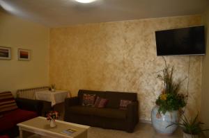 sala de estar con sofá y TV en la pared en Hotel La Piccola Stazione, en Torrita di Siena