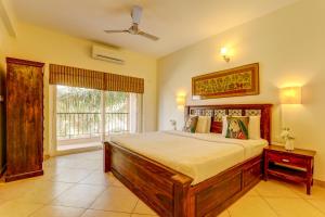 Heritage Nirvana Villa - 4BHK, Goa في كالانغيُت: غرفة نوم بسرير كبير ونافذة