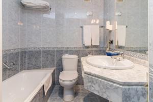 a bathroom with a tub and a toilet and a sink at Hotel Gijon in Gijón