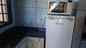 a microwave on top of a refrigerator in a kitchen at Aguas Lindas de Itacuruça in Itacuruçá