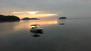 ein kleines Boot im Wasser bei Sonnenuntergang in der Unterkunft Aguas Lindas de Itacuruça in Itacuruçá