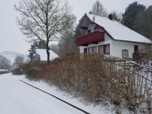 a white house with a red roof in the snow at Ferienhaus im Seepark Kirchheim in Kirchheim