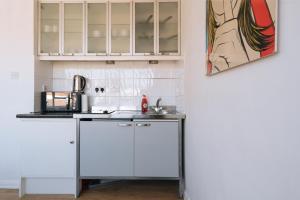 een keuken met witte kasten en een schilderij aan de muur bij Modern Studio Flat. Central London. Zone 1. in Londen