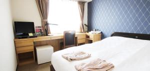 a bedroom with a bed and a desk with a television at Takamatsu City Hotel in Takamatsu