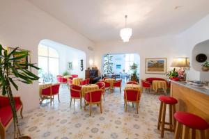 a dining room with red chairs and tables at Hotel Candia in Ischia