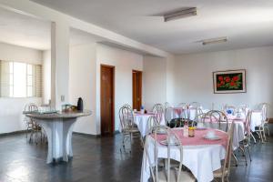 Zimmer mit Tischen und Stühlen sowie einem rosa und weißen Tischtuch in der Unterkunft Brasil Hotel in Três Pontas