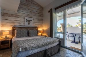 a bedroom with a bed and a balcony with a table at Le Mas de Cocagne in Saintes-Maries-de-la-Mer