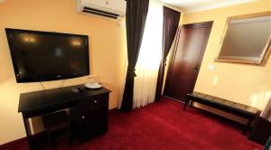 a hotel room with a television and a red carpet at La Storia Guest House in Piteşti