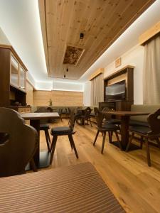 a waiting room with tables and chairs and a television at Hotel Stella Alpina in Andalo