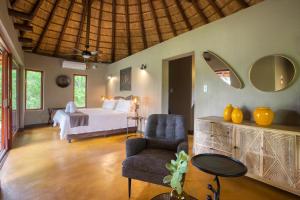 a bedroom with a bed and a chair and a table at Emhosheni River Lodge in Balule Game Reserve