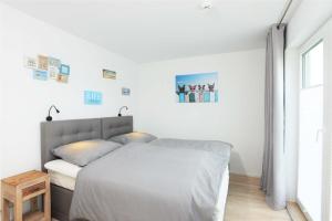 a white bedroom with a bed and a window at Marina Villa in Olpenitz