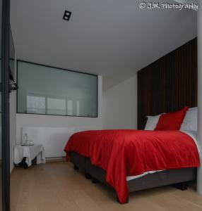 una camera con un letto con una coperta rossa di James & Leon a Ostenda