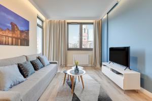 a living room with a couch and a tv at Apartment Long Gardens TriApart® in Gdańsk