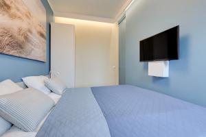 a bedroom with a bed with a tv on the wall at Apartment Long Gardens TriApart® in Gdańsk