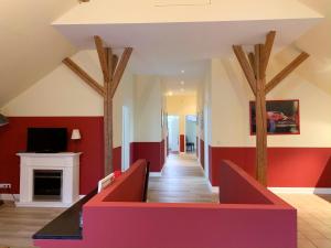 a living room with red and white walls and a fireplace at Gut Aspern Polohof in Barmstedt