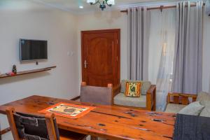 sala de estar con mesa de madera y TV en Upland Estates Serviced Apartments, en Lusaka